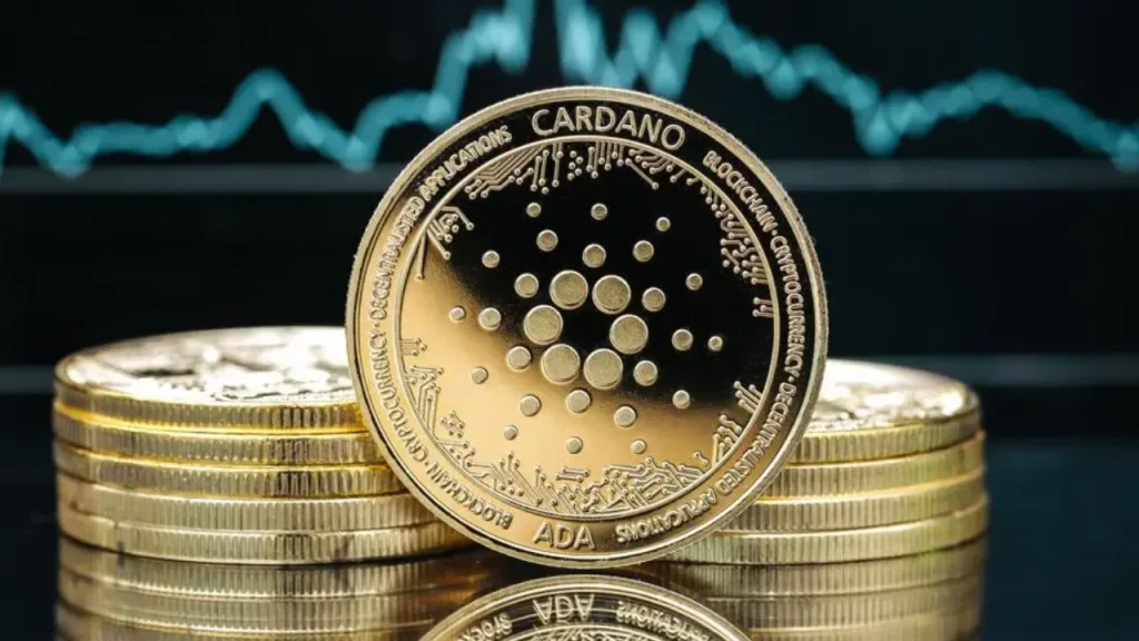 Gold Cardano (ADA) coin with a dotted circular logo standing on a stack of coins, with a teal line chart in the background.